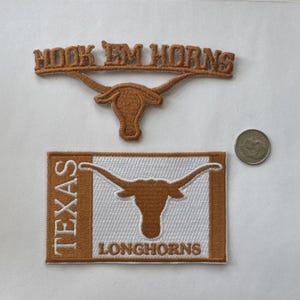 May include: Two embroidered patches with the words "HOOK EM HORNS" and a longhorn logo. A rectangular patch with the words "TEXAS LONGHORNS" and a longhorn logo. A silver coin is also in the image.