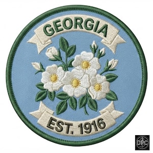May include: A circular embroidered patch featuring a light blue background with a central cluster of white flowers with yellow centers and green leaves. The text GEORGIA is arched at the top and EST. 1916 is at the bottom on white banners.