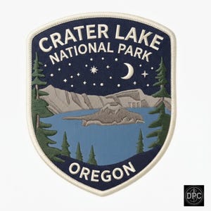 May include: A shield-shaped embroidered patch featuring a night scene of Crater Lake National Park in Oregon. The design includes a dark blue sky with a crescent moon and stars, light blue water, grey mountains, and green pine trees.