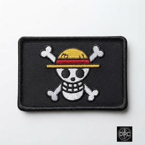 May include: A rectangular black embroidered patch featuring a white skull and crossbones design. The skull wears a yellow straw hat with a red band. The patch has a thick black stitched border and a flat, textured surface with detailed thread work.