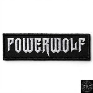 May include: A rectangular embroidered patch featuring a black background with the word POWERWOLF stitched in white capital letters. The font has a sharp, angular design with a distinct pointed extension on the letter W in the center.