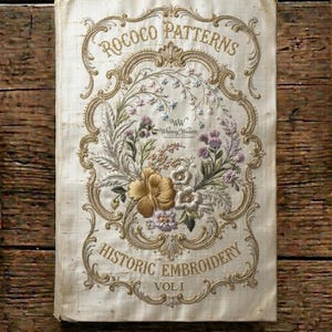 May include: A cream-colored fabric book cover featuring gold embroidered Rococo Patterns and Historic Embroidery Vol I text. The center displays a detailed floral arrangement with gold, purple, and green threads inside an ornate gold frame.