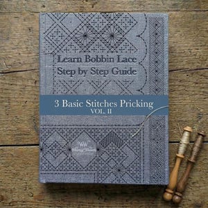Può includere: Un libro di istruzioni grigio intitolato Learn Bobbin Lace Step by Step Guide, 3 Basic Stitches Pricking Vol. II, con motivi geometrici in pizzo nero sulla copertina e il logo Whimsy Weaver, accompagnato da due fuselli in legno.