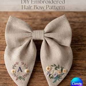 以下が含まれることがあります： DIY Embroidered Hair Bow Patternという文字が書かれたベージュの布製ヘアリボン。左側には文字Aを囲む花輪が、右側には黄色、青、緑の刺繍された花のクラスターが施されています。