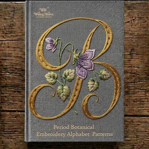May include: A gray hardcover book titled Period Botanical Embroidery Alphabet Patterns. The cover features a large, gold-embroidered letter B intertwined with purple flowers and green leaves. The text WW Whimsy Weaver is printed at the top.
