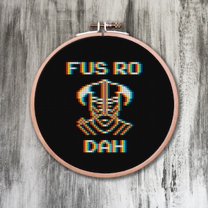 May include: A black embroidery hoop with a white pixelated image of a character from the video game "The Elder Scrolls V: Skyrim" with the text "Fus Ro Dah" above the character.