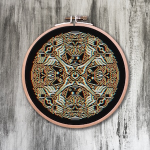 May include: A black and white embroidery hoop with a colorful geometric pattern. The pattern is a repeating design of abstract shapes and lines.