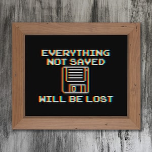 May include: A framed black and white pixel art print with the text "EVERYTHING NOT SAVED WILL BE LOST" and a pixel art image of a floppy disk.