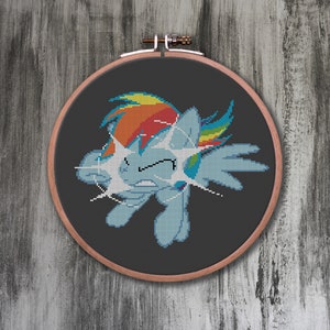 May include: A cross-stitch embroidery hoop with a colorful cartoon image of a pony with a rainbow mane and tail. The pony is depicted with a surprised expression and its eyes are wide open.