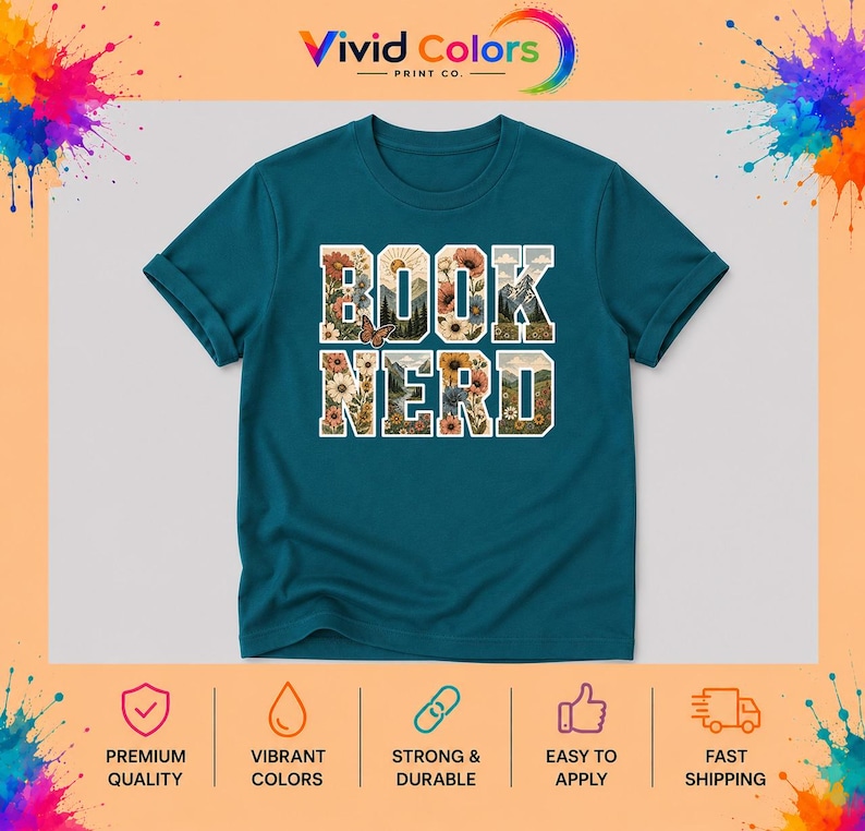 May include: A teal short-sleeved t-shirt featuring the text "BOOK NERD" in large block letters. The letters are filled with a graphic design of mountains, flowers, and a butterfly. The shirt has a crew neckline and a standard fit.