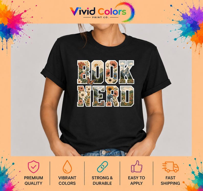 May include: A black short-sleeved t-shirt featuring the text BOOK NERD in large block letters. The letters are filled with a colorful graphic design of various flowers, green mountains, a sun, and a small butterfly on the letter O.