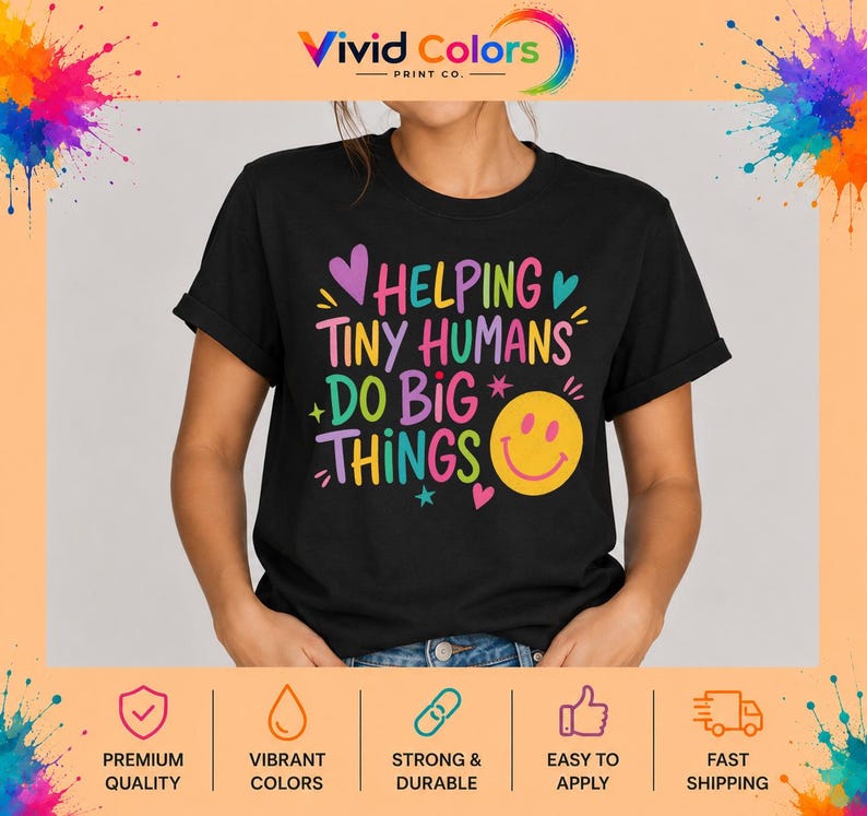 May include: A black short-sleeved t-shirt featuring the colorful text HELPING TINY HUMANS DO BIG THINGS in a mix of pink, yellow, blue, and purple fonts. The design includes small star and heart accents along with a large yellow smiley face icon.