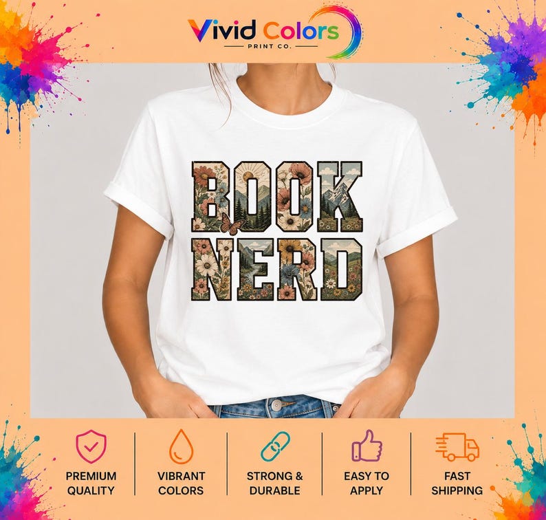 May include: A white short-sleeved t-shirt featuring the text BOOK NERD in large block letters. The letters are filled with a graphic design of colorful flowers, green mountains, a sun, and a small brown butterfly on a light background.