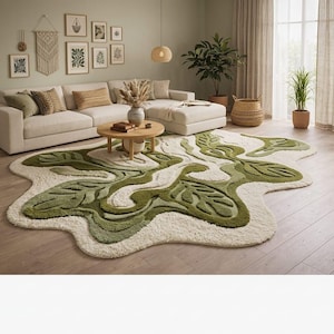 Może przedstawiać: Nowoczesny salon z kremową sofą i okrągłym drewnianym stolikiem kawowym. Duży dywan w kształcie liścia w odcieniach zieleni i kremu pokrywa podłogę. Pokój jest udekorowany oprawionymi dziełami sztuki, roślinami i wiklinowym koszem.