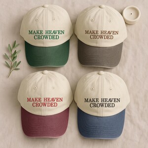 Peut inclure: Quatre casquettes de baseball avec le texte "MAKE HEAVEN CROWDED". Les casquettes ont une couronne crème et une visière colorée en vert, gris, bordeaux et bleu. Elles sont disposées sur un fond neutre.