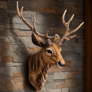 May include: A detailed, brown deer head wall mount with large antlers. The sculpture has realistic features, including dark eyes and textured fur, mounted on a stone-like wall.