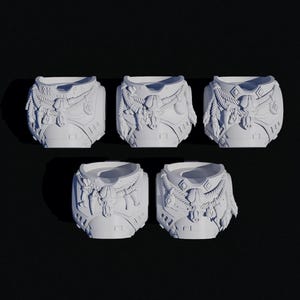 May include: Five white, decorative, cylindrical objects with intricate carved details. Each object features a textured surface with rope, tassels, and geometric patterns. The objects are arranged on a dark background.