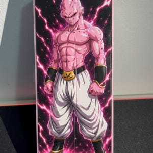 Könnte beinhalten: Ein rechteckiges rosa-schwarzes Grafikdesign mit der Figur Majin Buu aus Dragon Ball Z. Die Figur ist rosa mit weißer Hose, schwarzen Armbändern und einer goldenen Gürtelschnalle. Der Hintergrund hat rosa Blitze.