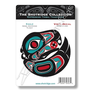 May include: A black, red, and teal vinyl decal featuring a stylized eagle design. The decal is part of The Shotridge Collection, which expresses tribal traditions. The text "EAGLE" is printed above the design, followed by "ISRAEL SHOTRIDGE" and "TLINGIT". The text "VINYL DECAL" is printed in the upper right corner, followed by "MADE IN USA". The text "www.shotridge.com" is printed at the bottom of the decal.