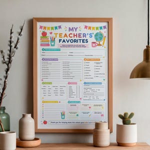 May include: A framed "My Teacher's Favorites" questionnaire poster with a light wood frame. The white paper features colorful graphics of books, a globe, and pencils, with sections for teacher information, gift card preferences, and personal interests.