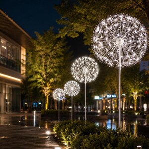 Può includere: Una serie di quattro luci da giardino illuminate a forma di dente di leone disposte in fila. Ogni luce presenta un sottile stelo in metallo argentato sormontato da un grande grappolo sferico di luci LED bianche che si irradiano verso l'esterno.