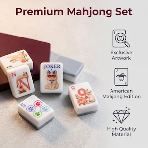 May include: A Premium Mahjong Set featuring white tiles with cat illustrations, floral accents, and paw prints. Tiles include a Joker card, the letter N, and the number 9. Text includes Exclusive Artwork, American Mahjong Edition, and High Quality Material.