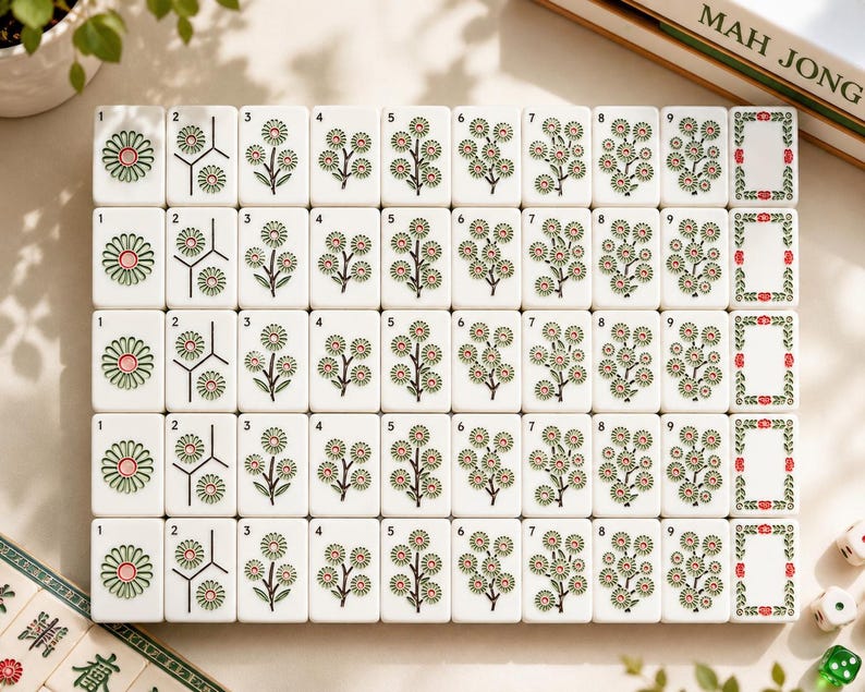 May include: A set of white Mahjong tiles arranged in a grid, featuring floral illustrations in green, pink, and black. Each tile displays a number from one to nine, with the final column showing blank tiles framed by green and red floral borders.