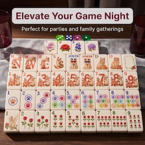 May include: A set of cream-colored mahjong tiles featuring cat illustrations, floral patterns, and colorful paw prints. The tiles include numbered sets, joker tiles with cat faces, and directional tiles labeled N, W, E, S, D, and F. Four dice are visible.