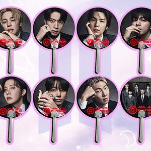 Puede incluir: Ocho abanicos de mano con retratos de un grupo musical. Cada abanico tiene un diseño circular con un retrato, un acento rojo y blanco y un mango plateado. Los abanicos están sobre un fondo lila claro.