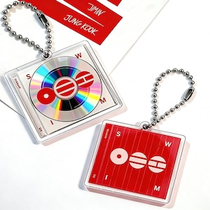 May include: Two square keyrings with silver ball chains. One keyring features a CD design with rainbow colours and red accents. The other keyring has a red background with white circular and horizontal line designs. The text "JIMIN" and "JUNG KOOK" is visible.