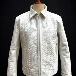Puede incluir: Una chaqueta blanca con un patrón texturizado de piel de cocodrilo en toda la prenda. La chaqueta incluye un cuello estándar, un cierre de cremallera frontal completo y dos bolsillos laterales con cremalleras, exhibida sobre un maniquí.