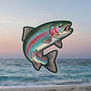May include: An embroidered patch shaped like a rainbow trout fish. The fish features a dark green back with black spots, a vibrant pink lateral stripe, and a white underbelly. The fins and tail are detailed with fine stitching in shades of pink and grey.