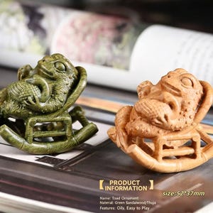 May include: Two wooden toad ornaments, one green and one brown, each carved in detail and seated on a miniature rocking chair. The green toad is painted with a darker shade of green. The size is 2 x 1.5 inches.