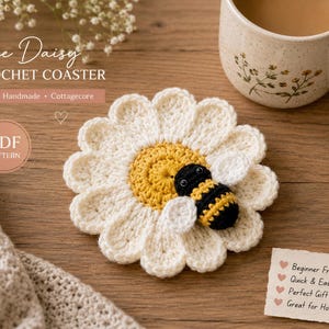 May include: A crochet coaster shaped like a white daisy with a yellow centre and a small black and yellow striped bee attached. The text reads Bee Daisy CROCHET COASTER, PDF PATTERN, and lists features including Beginner Friendly, Quick & Easy.