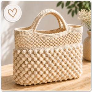 Könnte beinhalten: Eine cremefarbene Häkeltasche mit einem strukturierten Noppenmuster im unteren Bereich und einem offenen, rautenförmigen Netzdesign im oberen Teil, ausgestattet mit zwei integrierten Griffen und einem strukturierten rechteckigen Boden.