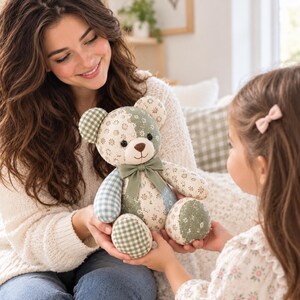 May include: A stuffed teddy bear crafted from patchwork fabric featuring various patterns in shades of sage green, cream, and light blue. The bear has a solid sage green ribbon tied around its neck, dark button eyes, and a stitched brown nose.