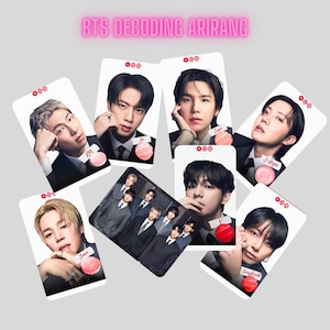 May include: A collection of seven rectangular trading cards featuring portraits of the members of BTS, each labeled with their name and a small circular icon. The text BTS DECODING ARIRANG is displayed at the top in pink lettering.