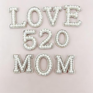 Può includere: Lettere e numeri decorativi che compongono le parole "LOVE", "520" e "MOM". Ogni lettera e numero è impreziosito da perle finte e strass, su uno sfondo rosa tenue. Ideale per lavori artigianali e regali personalizzati.
