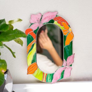 Stained glass floral mirror on table with plant reflection and soft interior light