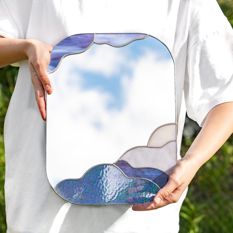 Stained glass cloud mirror held in hands outdoor with soft natural light