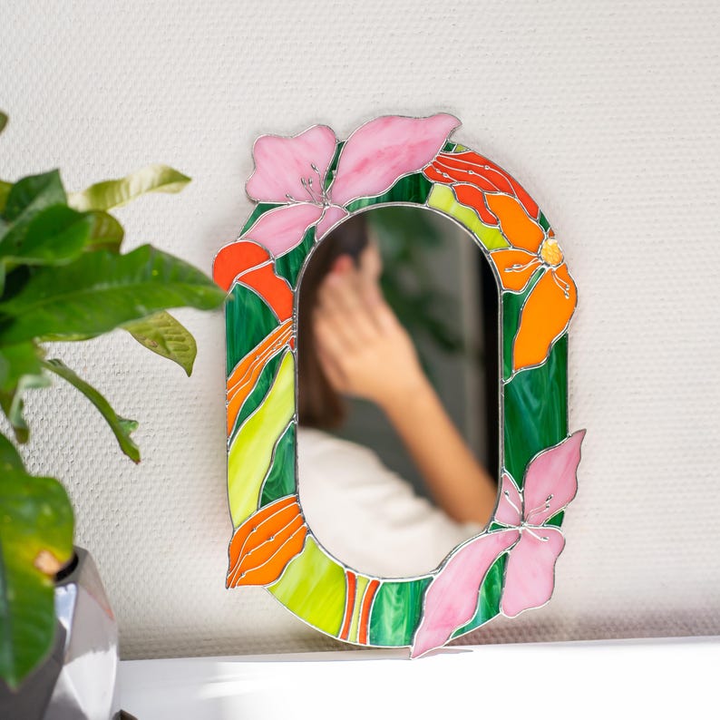Stained glass floral mirror on table with plant reflection and soft interior light