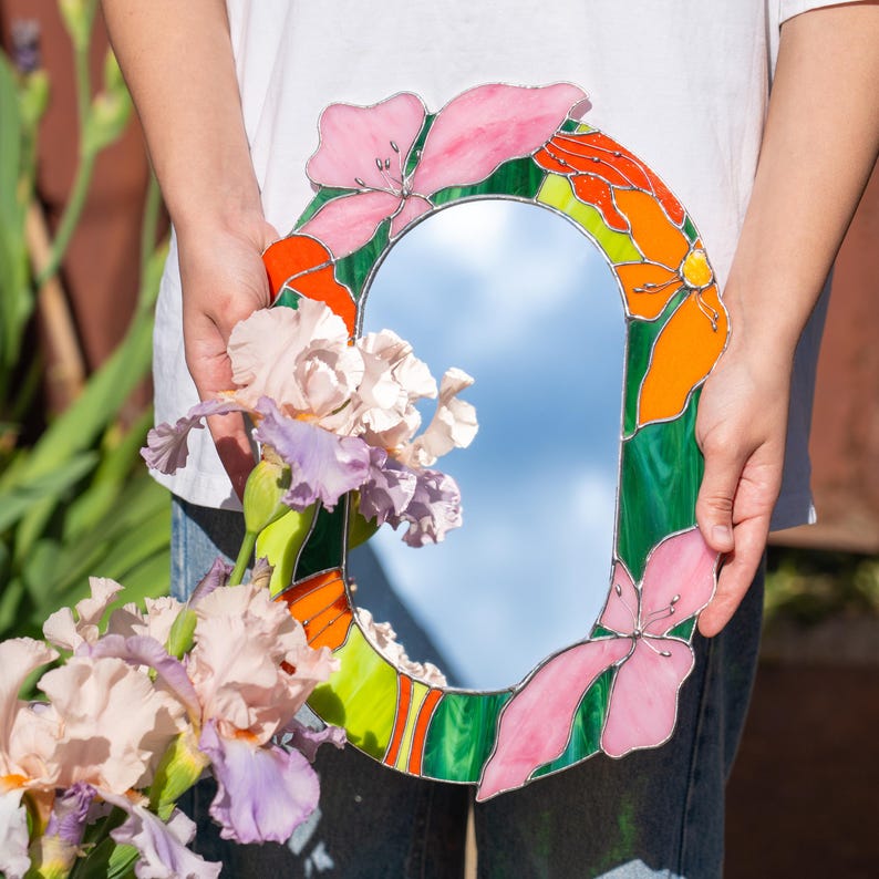 Stained glass floral mirror with pink flowers styled with irises in sunlight