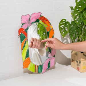 Stained glass floral mirror with hand reflection and decorative home setup