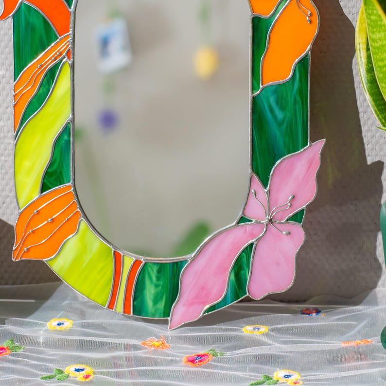 Detail of stained glass floral mirror base with pink petals and orange glass accents