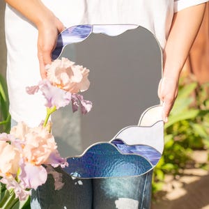 Stained glass cloud mirror held with flowers in soft sunlight outdoor