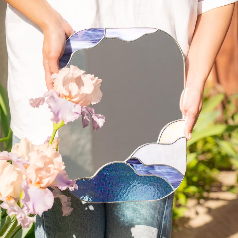 Stained glass cloud mirror held with flowers in soft sunlight outdoor