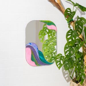 Stained glass colorful waves mirror on wall with green monstera plant modern home decor