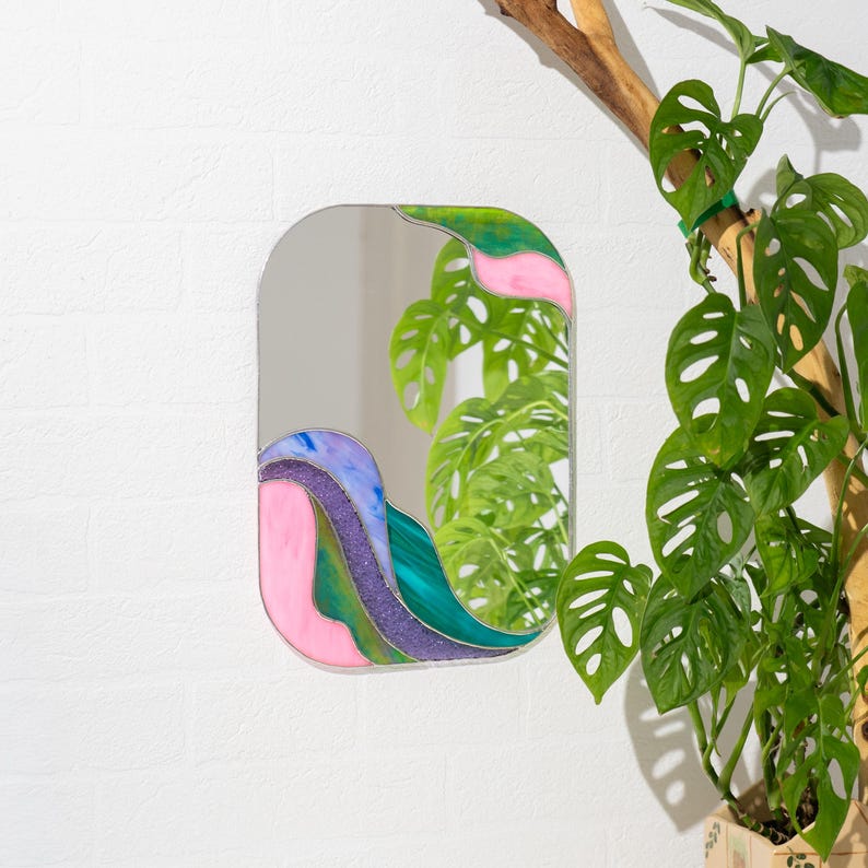 Stained glass colorful waves mirror on wall with green monstera plant modern home decor