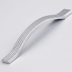 May include: A polished silver-toned metal cabinet handle featuring a gentle, elongated S-curve shape. The surface of the handle is detailed with three distinct, parallel longitudinal grooves that run along the entire length of the hardware.