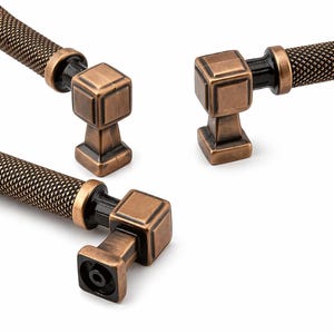 Peut inclure: Gros plan sur quatre poignées de meubles de couleur bronze. Chaque poignée présente un design géométrique carré avec une poignée texturée. Les poignées sont posées sur un fond blanc, soulignant leur finition antique et leur savoir-faire détaillé.